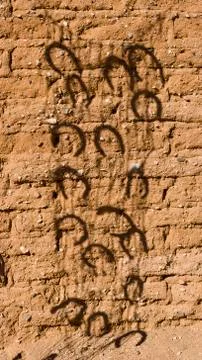Horseshoe Shadow Projected on Old Adobe Wall Stock Photos
