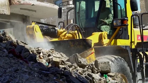 Hose pipe damps down dust as rubble is cleared from streets of Raqqah, Syria Stock Footage 94565332