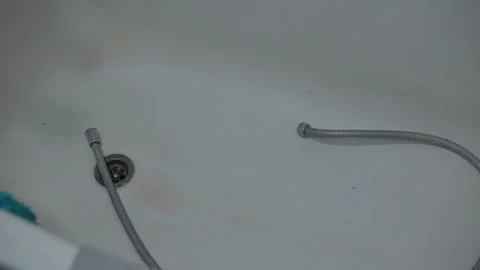 A hose is placed in a bathtub as water flows from it and heads toward the drain. Video stock 339090559