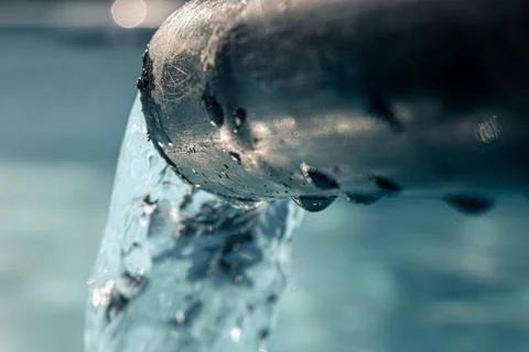 Hose pulling water jet in the foreground and filling a pool with water 写真素材