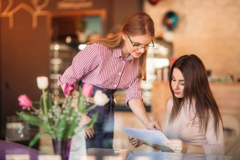 Hospitable waitress help to customer what to choose something from menu Foto stock