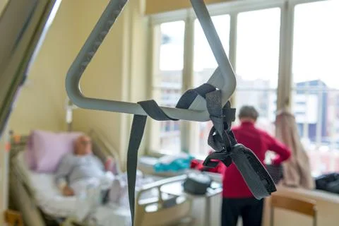 Hospital bed triangle with unrecognizable elderly couple in the background. Stock Photos