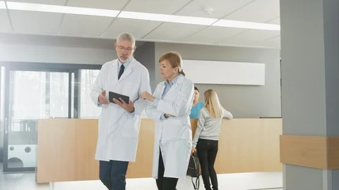 In the Hospital, Busy Doctors Talk, Using Tablet Computer While Walking Through Stock Footage 90168710