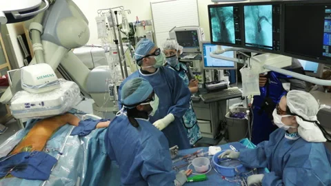 Hospital OR surgeons angioplasty heart stent fluoroscope monitors wideshot Stock Footage