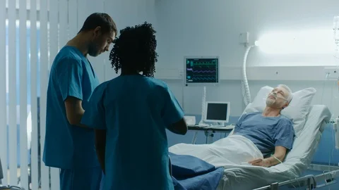 In the Hospital, Senior Man Sleeps in the Bed, Doctor and Nurse Have Discussion. Stock Footage