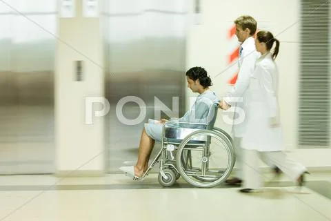Hospital Staff Pushing Man In Wheelchair, Blurred Motion