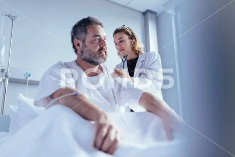 Hospitalised man getting examined by female physician Stock Photos