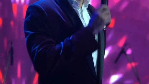 Host bearded man hold a microphone close up. Spotlights illuminate the scene. 스톡 동영상 119979451