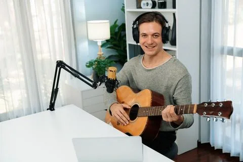 Host channel singer looking camera, playing guitar along singing. Pecuniary. Stock Photos