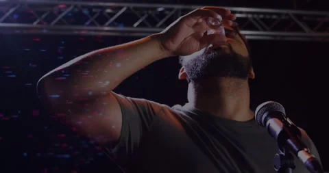 Host lifting shot glass starting drinking on comedy stage raising arm cheering Stock Footage 330917681