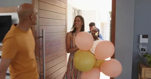 Host opening wooden front door, welcoming friends into modern home, accepting Stock Footage 321955156