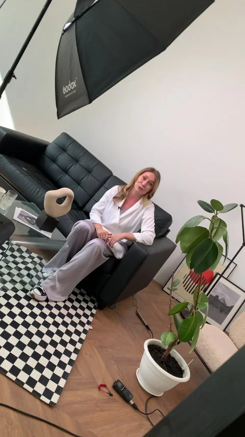 Host sits on couch in bright room engaged in conversation Video stock 303065137