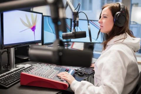 Host Using Headphones And Microphone While Looking At Monitor Stock Photos