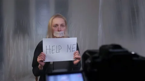 The hostage sits in front of a video camera with a placard reading Help me Stock-Footage 147726142
