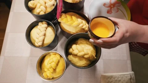 The hostess in the kitchen smears the Easter bread with a special mixture with Stock Footage 253917476