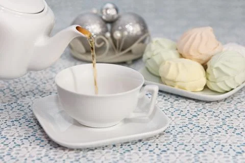 Hostess pours tea into cups from the kettle, in a piece with delicious fresh Stock Photos
