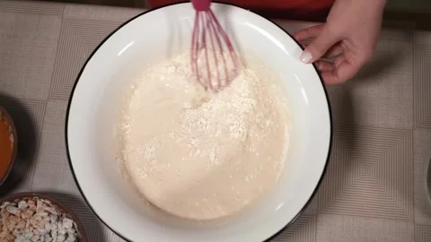 The hostess is preparing dough in the kitchen. Mix to a thick consistency Stock Footage 253486655