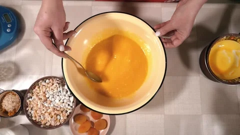 The hostess is preparing dough in the kitchen. Mixes beaten eggs with flour Stock Footage 253486662