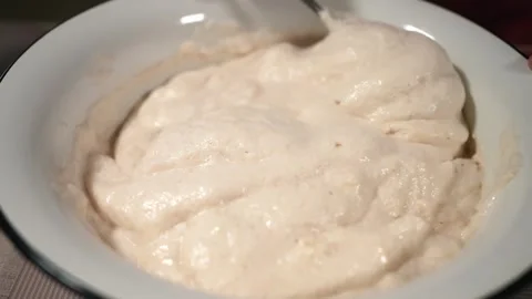 The hostess is preparing dough in the kitchen. Mixes beaten eggs with flour Stock Footage 253486670