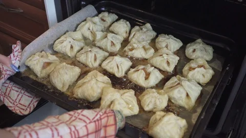The hostess pulls out of the oven delicious puffs with apricot Stock Footage 110835600