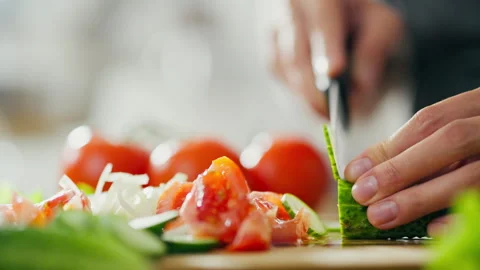 Hostess is slicing cucumber on cutting board. Close-up of housekeepers hands 動画素材 246750739
