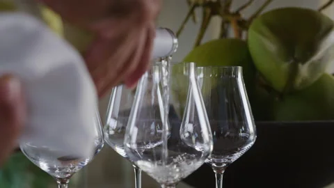 Host's hands pouring white wine in glasses on table of tropical beach resort Stock Footage 204842296