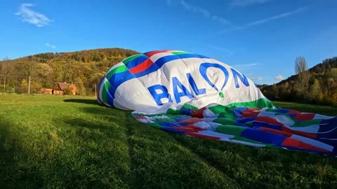 Hot air balloon during process preparation and launch in a green field on a sunn Stock Footage 242185530