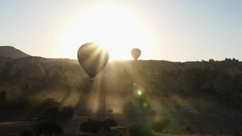 A hot air balloon flies parallel to the ground against a bright rising sun Stock Footage 238501056