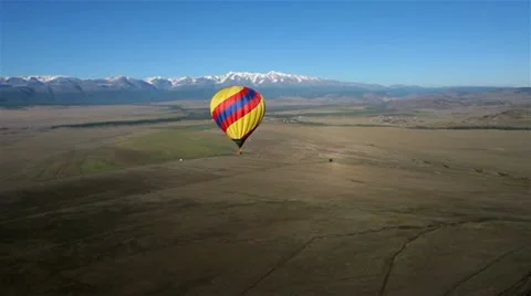 Hot Air Balloon flying across the sky in mountain landscape. Stock Footage