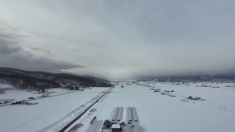 Hot Air Balloon Shadow Drifting Over Snowy Greenhouses in Furano Stock Footage 334454760