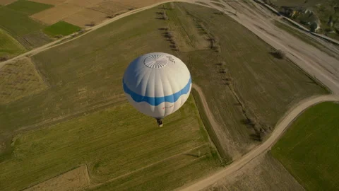 A hot air balloon soars over a field in Cappadocia. Drone Shot 4K Stock Footage 254775606