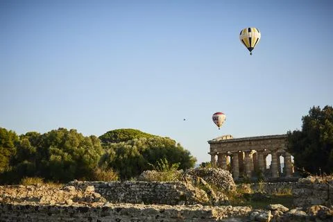 Hot air balloons float over ancient ruins in a rural scene, summer evening mo 스톡 사진
