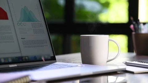 A hot and steaming cup of coffee on a desk with laptop . Stock Footage 127335237