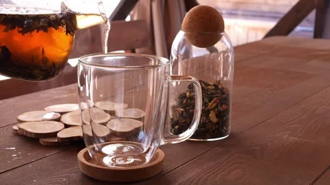 Hot aromatic herbal tea being poured into mug in gazebo in nature Experience Stock Footage 267403596