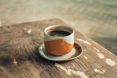 Hot black coffee cup placed on rustic vintage wooden table. Stock Photos