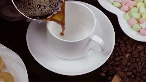 Hot Black coffee is poured into a white cup. Slow motion. Stock Footage 79050557