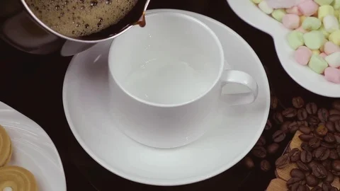 Hot Black coffee is poured into a white cup. Slow motion. Stock Footage 79050641