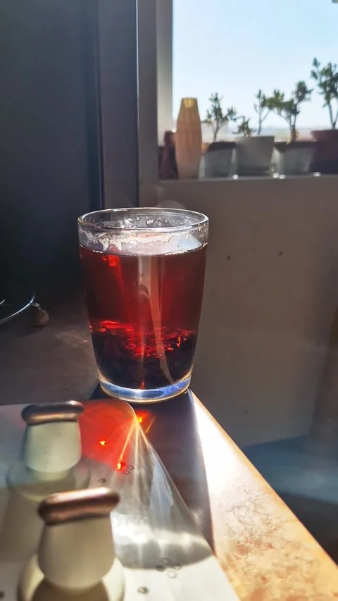 Hot Black Loose Leaf Tea in Glass Steaming in Bright Morning Sunlight Stock Footage 339078298