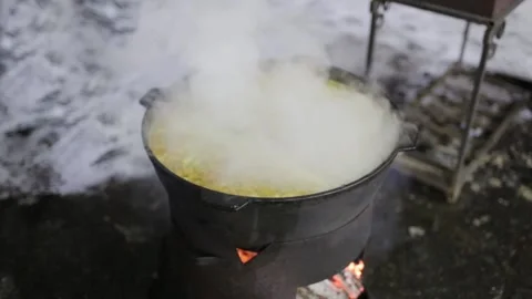 Hot boiling soup is cooked in a large cast-iron pot over an open fire Stock Footage 165279029