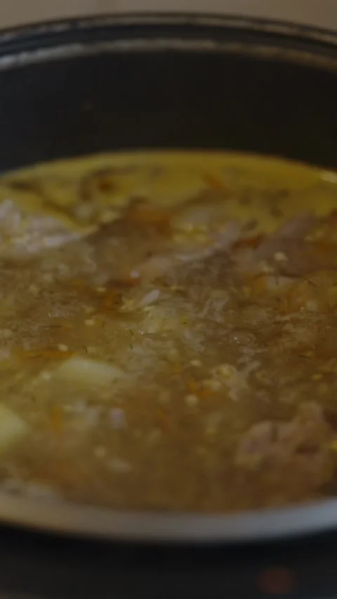 Hot boiling soup with vegetables inside dark metal cooking pot Stock-Footage 338023026