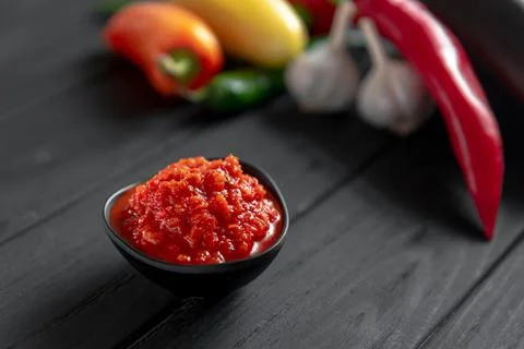 Hot chili pepper paste. Red sauce on a wooden background. Ajika or ajika in Stock Photos