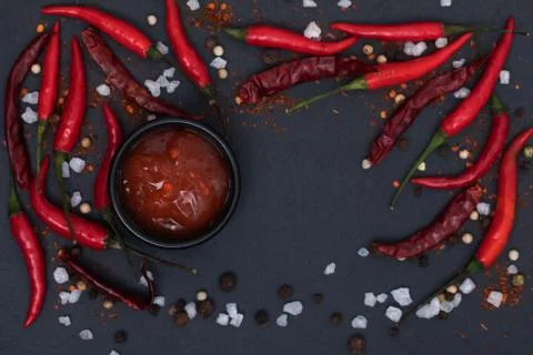 Hot chilli sauce paste with fresh and cracked pepper on black slate backgroun Stock Photos