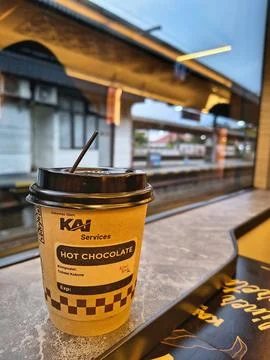 Hot chocolate cup on a train table with station view from window Stock Photos