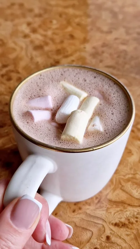 Hot Chocolate with Marshmallows in White Mug Held by Hand on Wooden Table Stock Footage 339003801
