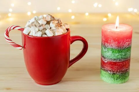 Hot chocolate in mug with marshmallows and candy cane, Christmas candle on table Foto stock