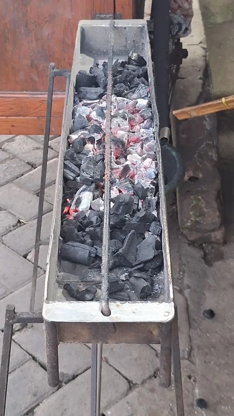 Hot coals burning in a brazier ready to grill Indonesian satay Stock Footage 289210105