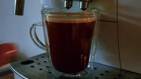Hot coffee being poured into white cup with crema in warm morning light 스톡 동영상 337257071