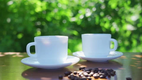 A hot coffee drink in two cups with scattered coffee beans on the table Stock Footage 201917243