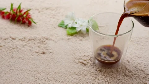 Hot coffee pouring into double wall glass on sand beach. Stockbeeldmateriaal 203391565