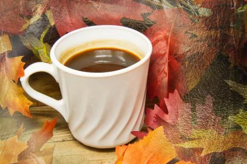 Hot coffee surrounded by fall colored leaves on a wood surface with texture. 스톡 사진